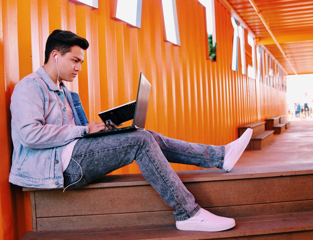 young man sitting outside with laptop